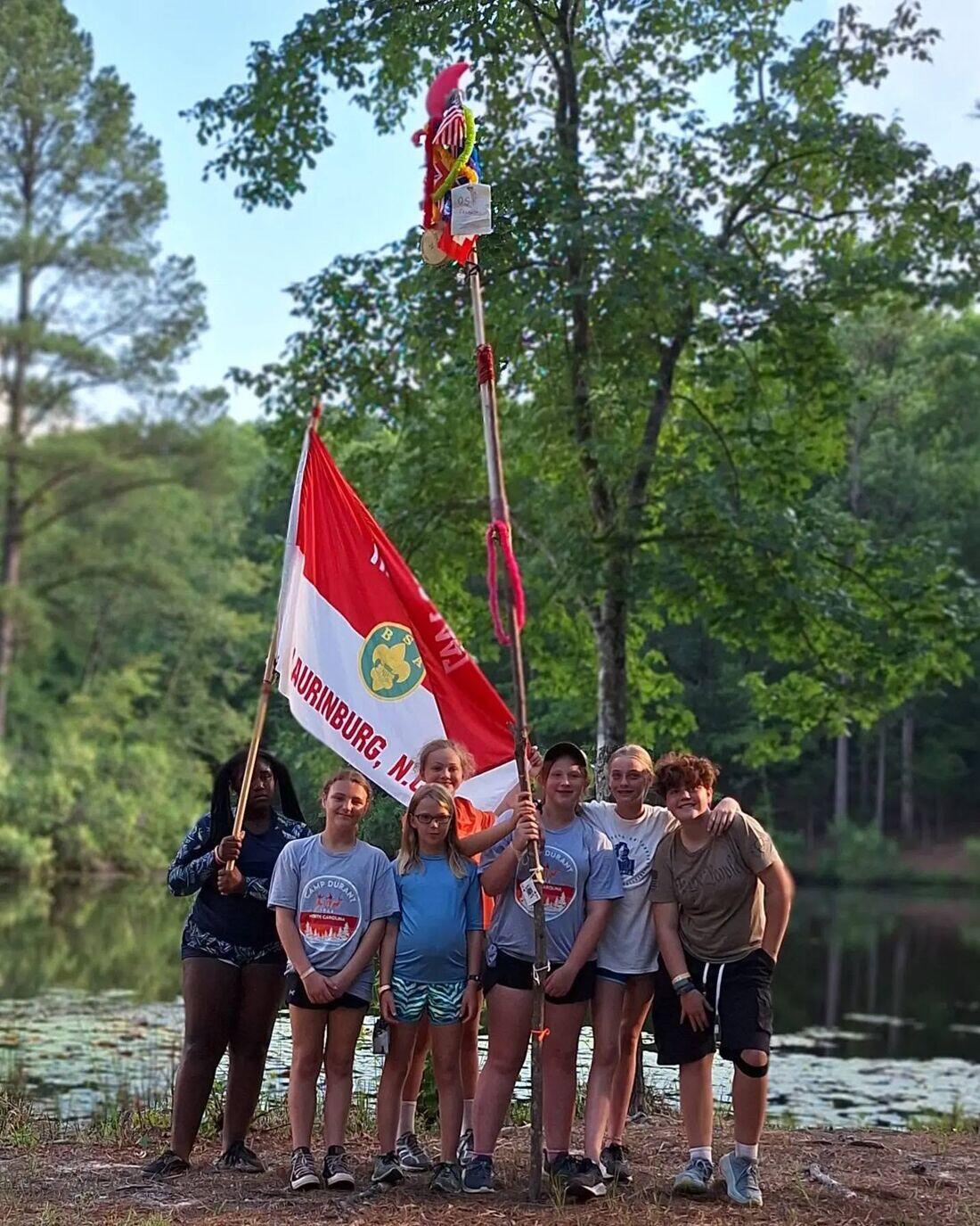 Scouts from Troop 1447 at summer camp holding a North Carolina flag marked Laurinburg, N.C.